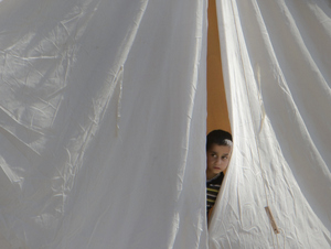 In this June 14, 2011 file photo, a Syrian refugee boy peers from a tent, in a camp, in Boynuyogun, Turkey. What appeared an unstoppable groundswell for change across the Middle East earlier this year, has splintered into scattered and indecisive conflicts that have left thousands dead and Western policy makers juggling roles ranging from NATO airstrikes in Libya to worried bystanders in Syria and Yemen.(AP Photo/Vadim Ghirda,File)