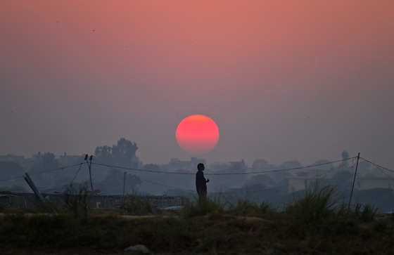 A Pakistani boy is silhouetted against sunset as he watches his friends playing cricket at a field on the outskirts of Islamabad, Pakistan, Wednesday, Oct. 31, 2012. (AP Photo/Anjum Naveed)